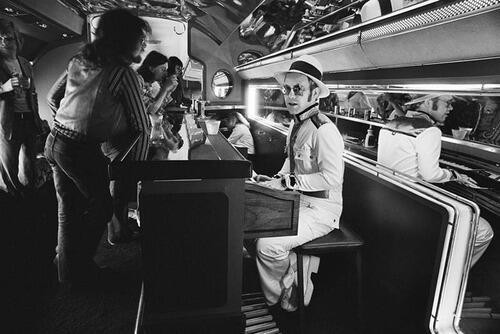 Elton John hrá na piano na palube svojho súkromného lietadla v roku 1976